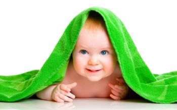 Baby smiling under green blanket